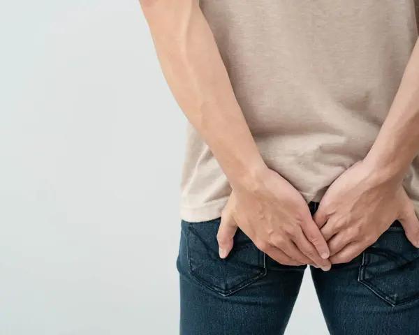 Osoba trzymająca się za pośladki, sugerująca problem z krwią z odbytu. Jaki lekarz może pomóc?