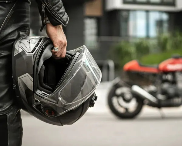 Motociclista con casco, simbolo di sicurezza e certificazione casco moto. Moto rossa sfocata sullo sfondo.