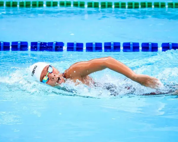 Un nageur concentré en pleine séance natation, la tête hors de l'eau, les bras en mouvement dans la piscine.