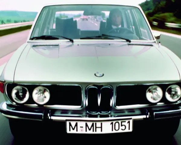 Srebrne BMW E3 z lat 70. jedzie po drodze.