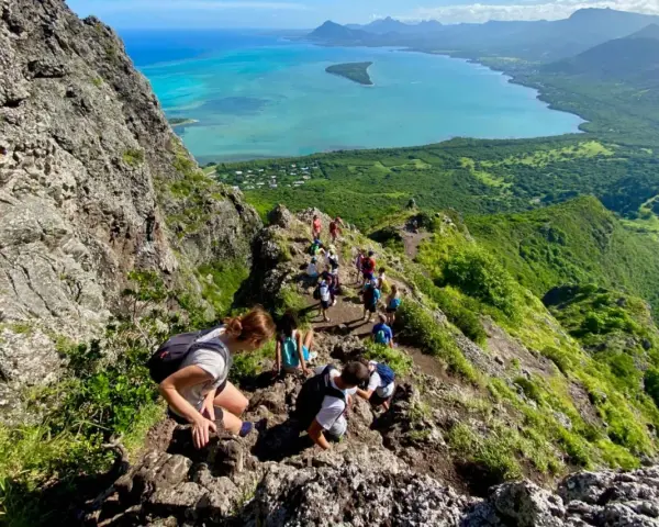 Grupa turystów wędruje po skalistym szlaku na Le Morne Mauritius, podziwiając zapierający dech w piersiach widok na turkusową lagunę i zielone wzgórza.