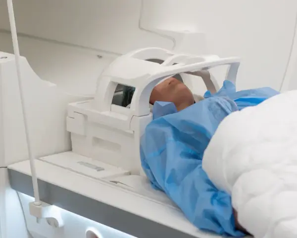 Pacjent leży w aparacie do rezonansu magnetycznego głowy, przygotowany do badania.