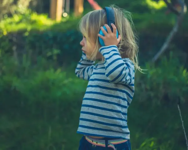 Ein Kind mit Kopfhörern im Freien, das die Welt der Klänge entdeckt. Diese Szene zeigt die Reizoffenheit bei Kindern, die sich neugierig auf neue Erfahrungen einlassen.