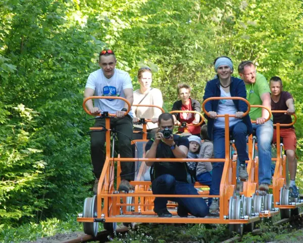 Rodzina na drezynach w Bieszczadach, ciesząca się zielenią i słońcem. Radość i wspólna przygoda na torach.