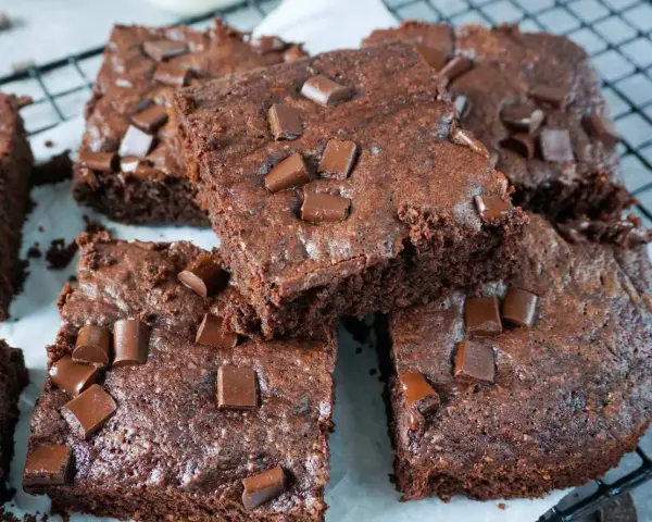 Saftige Zucchini Brownies mit Schokostückchen, die auf einem Gitterrost liegen.