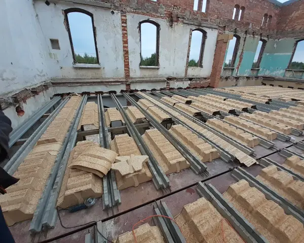 Rozpoczęła się wymiana stropu w starym domu. Metalowe belki i prefabrykowane elementy stropowe czekają na montaż.