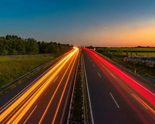 Ljusspår av bilar på en tysk autobahn vid solnedgången.