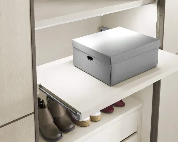 Un ripiano estraibile fai da te, con una scatola grigia sopra e scarpe sotto, ottimizza lo spazio in un armadio moderno.