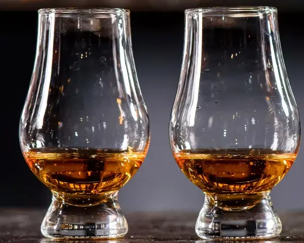 Drei Gläser mit bernsteinfarbenem Whisky stehen nebeneinander. Ein Blick auf die Whisky Kalorien für Genießer.