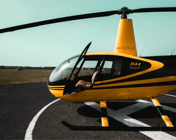Żółto-czarny helikopter Robinson R44 Raven II na płycie lotniska. Marzysz, jak zostać pilotem helikoptera?