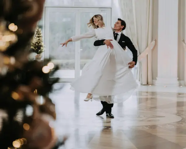 Para pierwszy taniec bez stresu, kursy online czy szkoła tańca? Młoda para w eleganckich strojach wiruje na parkiecie, tworząc romantyczną atmosferę.