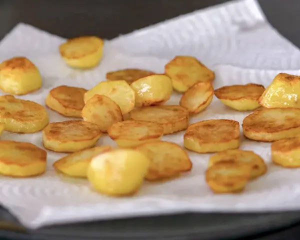 Patatas al horno doradas y crujientes, recién salidas del horno y reposando sobre papel absorbente. ¡Un manjar listo para disfrutar!