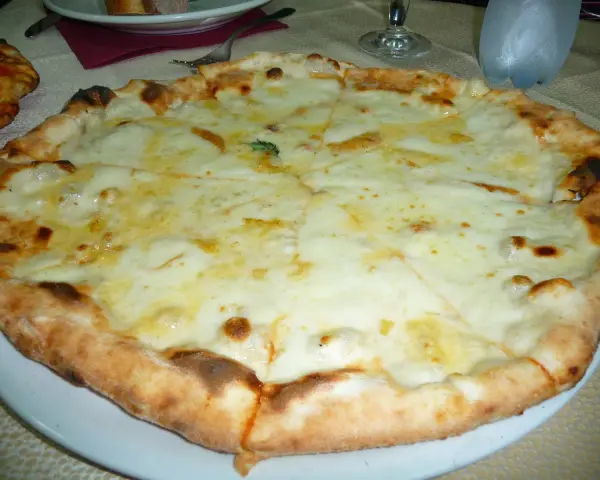 Pizza 4 formaggi appena sfornata, con crosta dorata e abbondante formaggio fuso.