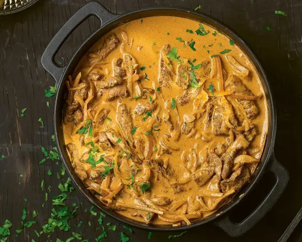 En gryta med krämig biff stroganoff, perfekt för ett mysigt middagsrecept. Garnerad med färsk persilja.