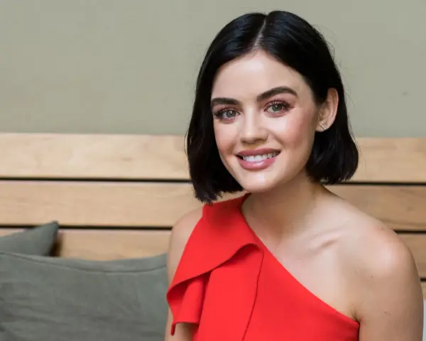 Lucy Hale sorride con un vestito rosso, ricordando i suoi film e programmi TV.