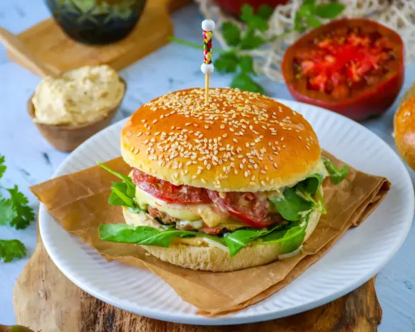 Un délicieux pain burger maison garni de légumes frais, de fromage fondant et d'une viande savoureuse. Un régal pour les yeux et les papilles !