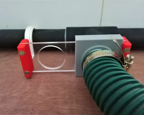 A 3d printed blast gate with a clear sliding mechanism and a green hose attached.