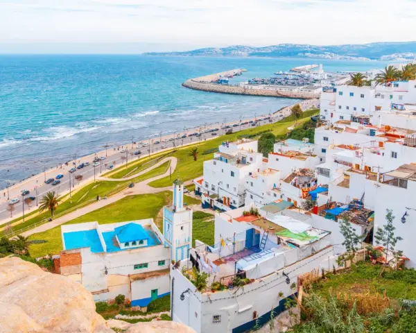 Widok na białe miasteczko z meczetem i turkusowym morzem, w oddali widać port. Tarifa Tanger prom.