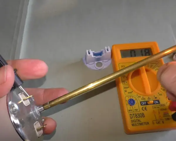 Come controllare un termostato con il tester: un multimetro digitale misura la resistenza di un componente metallico riscaldato.