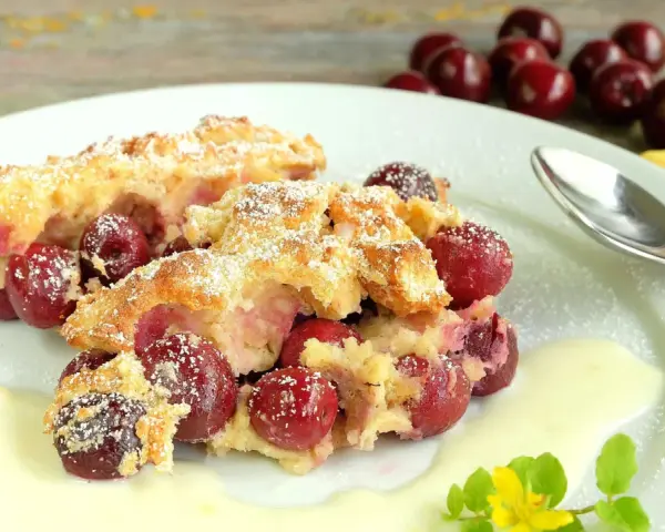 Zwei Portionen Kirschenmichel, ein köstliches Dessert, serviert mit Vanillesauce und bestäubt mit Puderzucker. Ein perfektes Kirschenmichel Rezept.