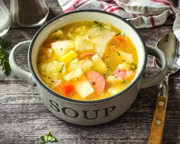 Herzhaftes Kohlsuppe Rezept mit Kartoffeln und Wurst in einer grauen Schüssel, bereit zum Genießen.