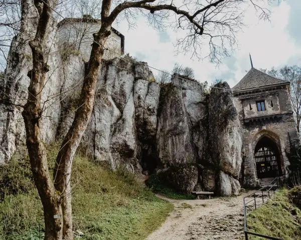 Ojcowski Park Narodowy atrakcje: ruiny zamku na skale, kamienna wieża bramna i ścieżka wśród zieleni.