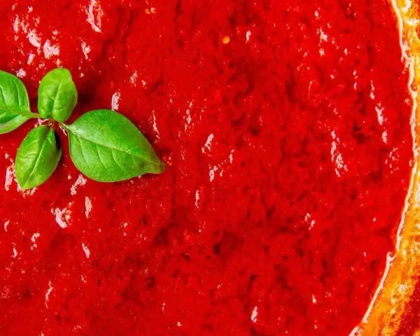 Leuchtend roter Sugo di Pomodoro mit frischen Basilikumblättern, bereit für Pasta.