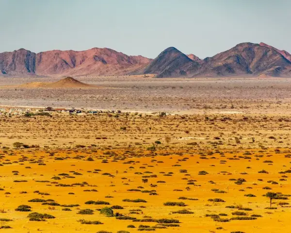 Pustynny krajobraz Namibii z górami w tle. Idealny czas na podróż do Namibii to okres od maja do października, kiedy jest sucho i chłodniej.
