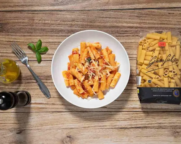 Macarrones a la napolitana servidos en un plato blanco, con un paquete de pasta Garofalo al lado.