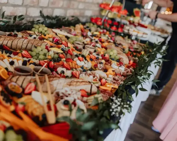 Stół pełen smakołyków na poprawiny: sery, wędliny, owoce, pieczywo i dipy. Idealna uczta po weselu.