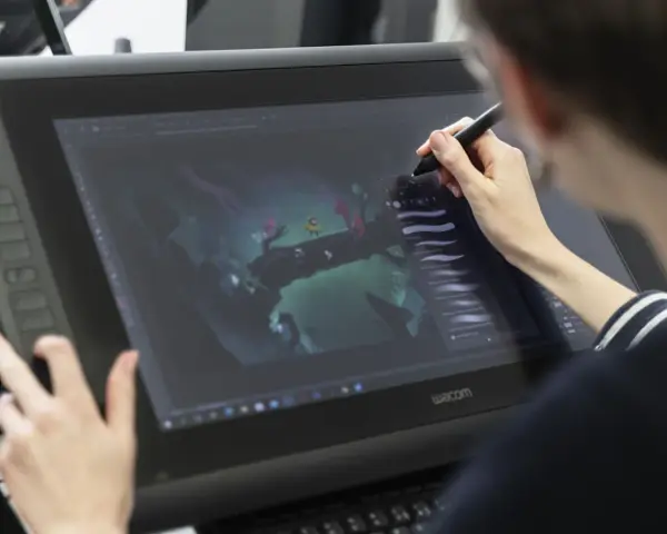 Person im Animation Studium nutzt Grafiktablett für digitale Kunst.
