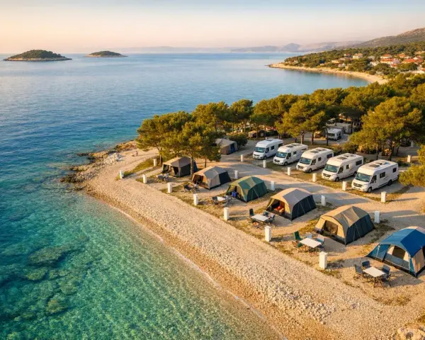 Idealny camping Chorwacja: namioty i kampery na kamienistej plaży, turkusowe morze, wyspy na horyzoncie.
