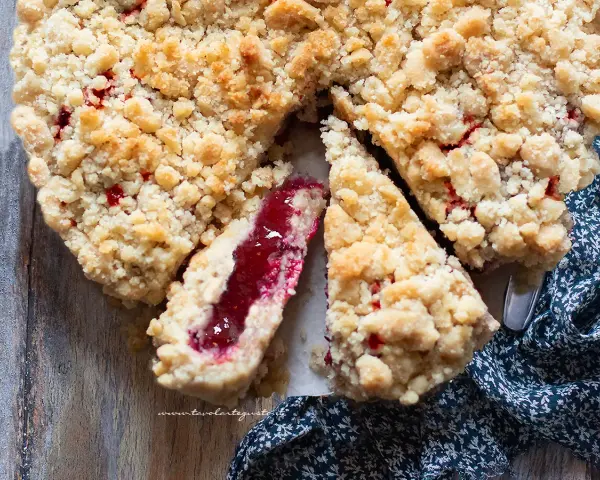 Sbriciolata alla marmellata con un ripieno rosso brillante e una crosta dorata e friabile, pronta per essere gustata.