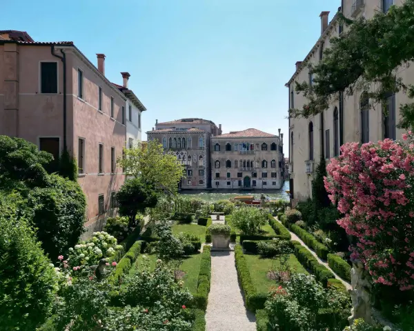 Giardini segreti a Venezia, con un canale e palazzi storici sullo sfondo. Un'oasi di pace tra il verde e i fiori.
