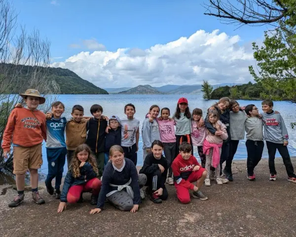 Un animateur pour combien de jeunes ? Un groupe d'enfants souriants pose devant un lac, prêts pour l'aventure.