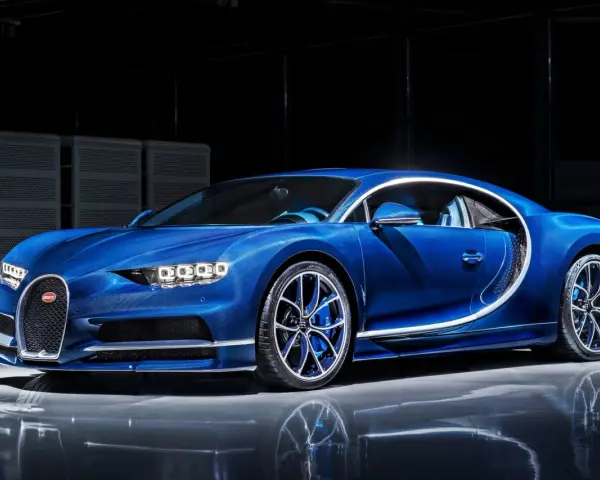 Niebieski Bugatti Chiron błyszczy w studio, jego aerodynamiczna linia podkreślona białym akcentem.