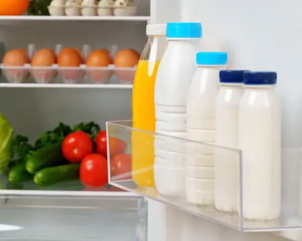 Bouteilles de lait et jus pour une bonne conservation lait frigo. Légumes frais sur l'étagère du bas.