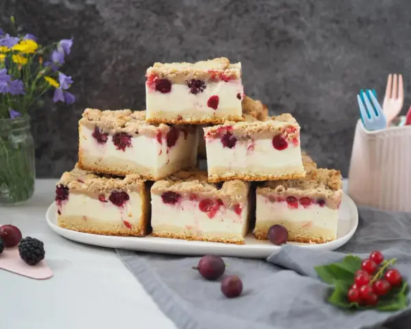 Stapel von saftigen Kuchenstücken mit Beeren und Streuseln – ein erfrischender Sommerkuchen, der Lust auf mehr macht.