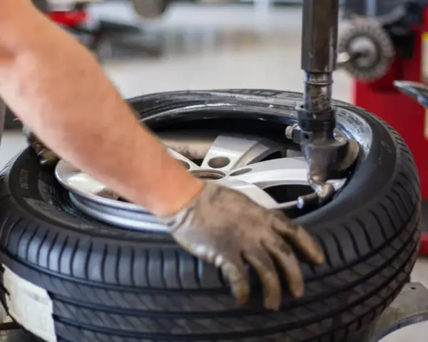 Un meccanico lavora su una gomma. La domanda su ogni quanti km si cambiano le gomme è importante per la sicurezza.