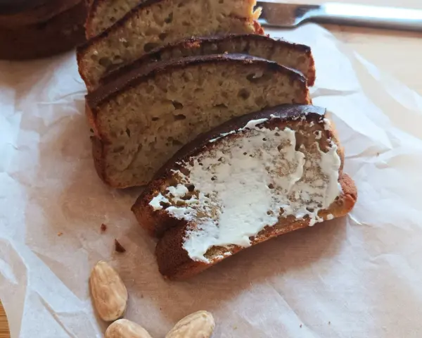 Pyszny chlebek bananowy z airfryera, pokrojony w kromki, jedna posmarowana masłem. Idealny na śniadanie.