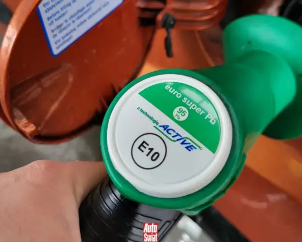 Dłoń trzyma zielony pistolet dystrybutora paliwa z napisem "euro super Pb 95 ACTIVE E10". To paliwo E5, które właśnie tankujesz.