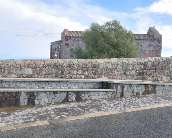 Fontana in pietra con scorci di un antico edificio religioso, un'oasi di pace ad **Allai, Sardegna**.