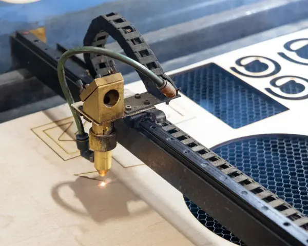 Macchina laser che sta per tagliare compensato, creando forme precise.