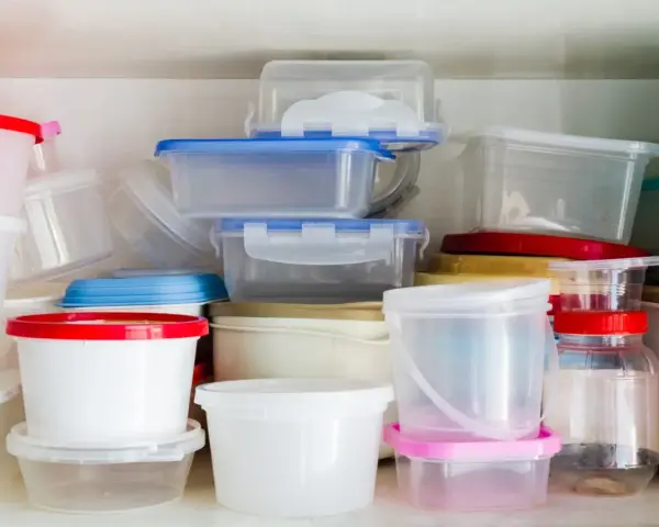 Stos pojemników na żywność, niektóre z kolorowymi pokrywkami. Uważaj na ftalany w plastiku.