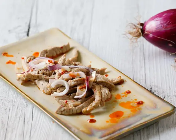 Straccetti di vitello conditi con cipolla rossa e un filo d'olio piccante, pronti per essere gustati.