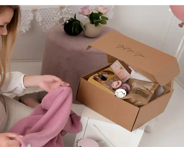 En blivande mamma inspekterar en presentkorg med nappar och hudvårdsprodukter.