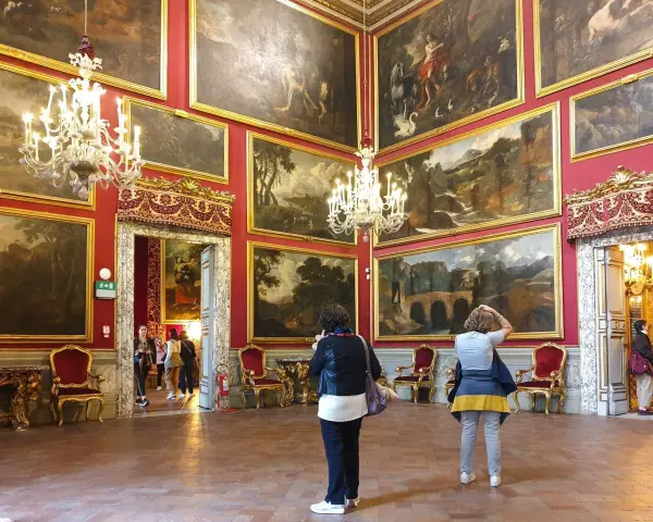 Wnętrze Galerii Doria Pamphilj z obrazami i żyrandolami.