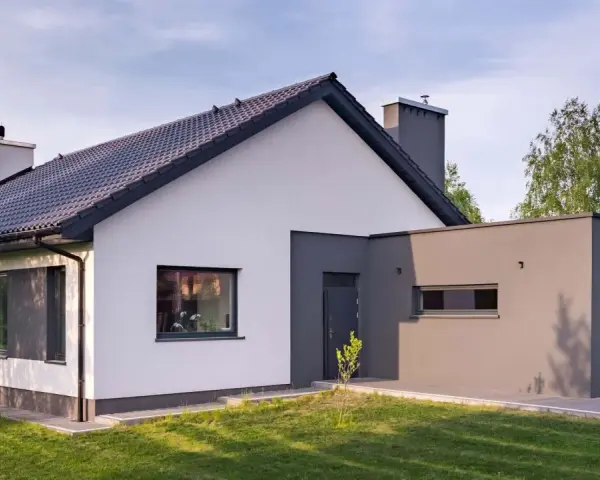 Nowoczesny dom z białymi i szarymi akcentami, prezentujący najmodniejsze kolory elewacji.