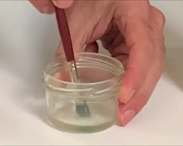 Pincel sumergido en un frasco con disolvente oleo, listo para limpiar.