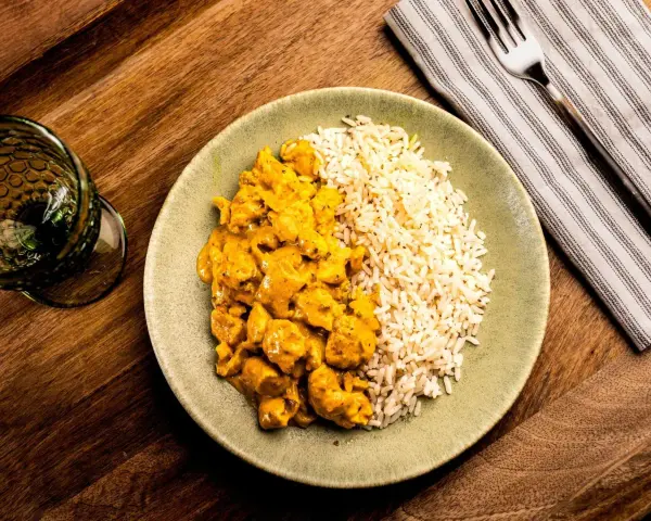 Plato de arroz con pollo en salsa curry, acompañado de arroz blanco. Un delicioso arroz con verduras y proteína.